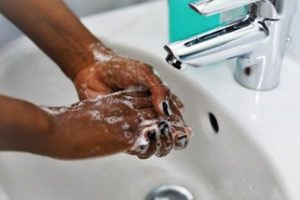 pictured: a pair of hands washes in a sink 