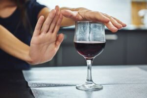 A hand pushes away in front of a glass of red wine | Wake Clinical Research
