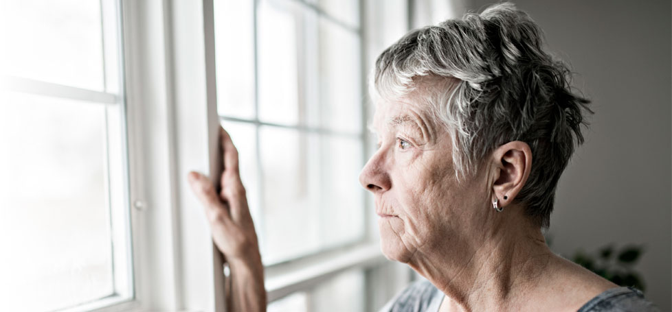 pictured: an elderly and melancholy woman stares out of a window
