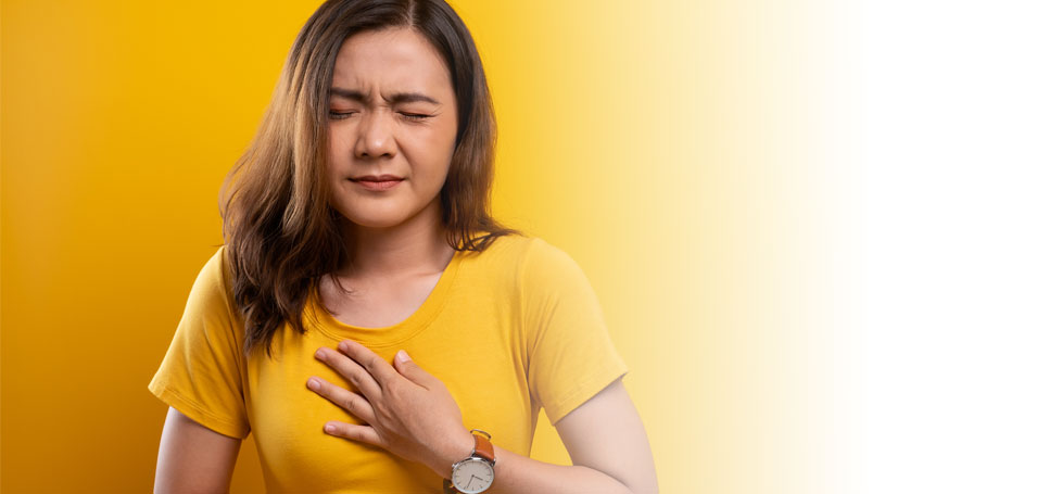 pictured: a woman grimaces in pain with one hand on her chest and one hand on her stomach