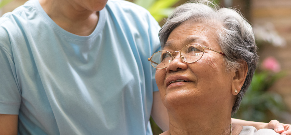 pictured: an elderly woman smiles up at a caregiver